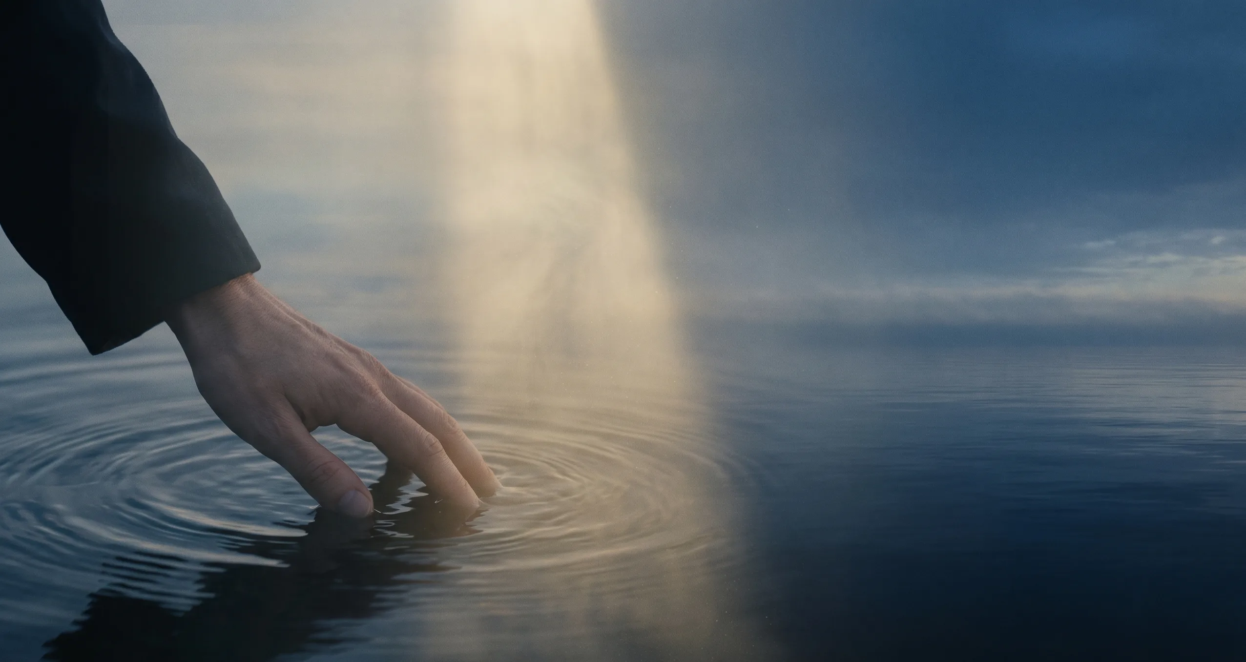 Trois visages d'une seule réalité — main touchant l'eau, lumière dorée, océan