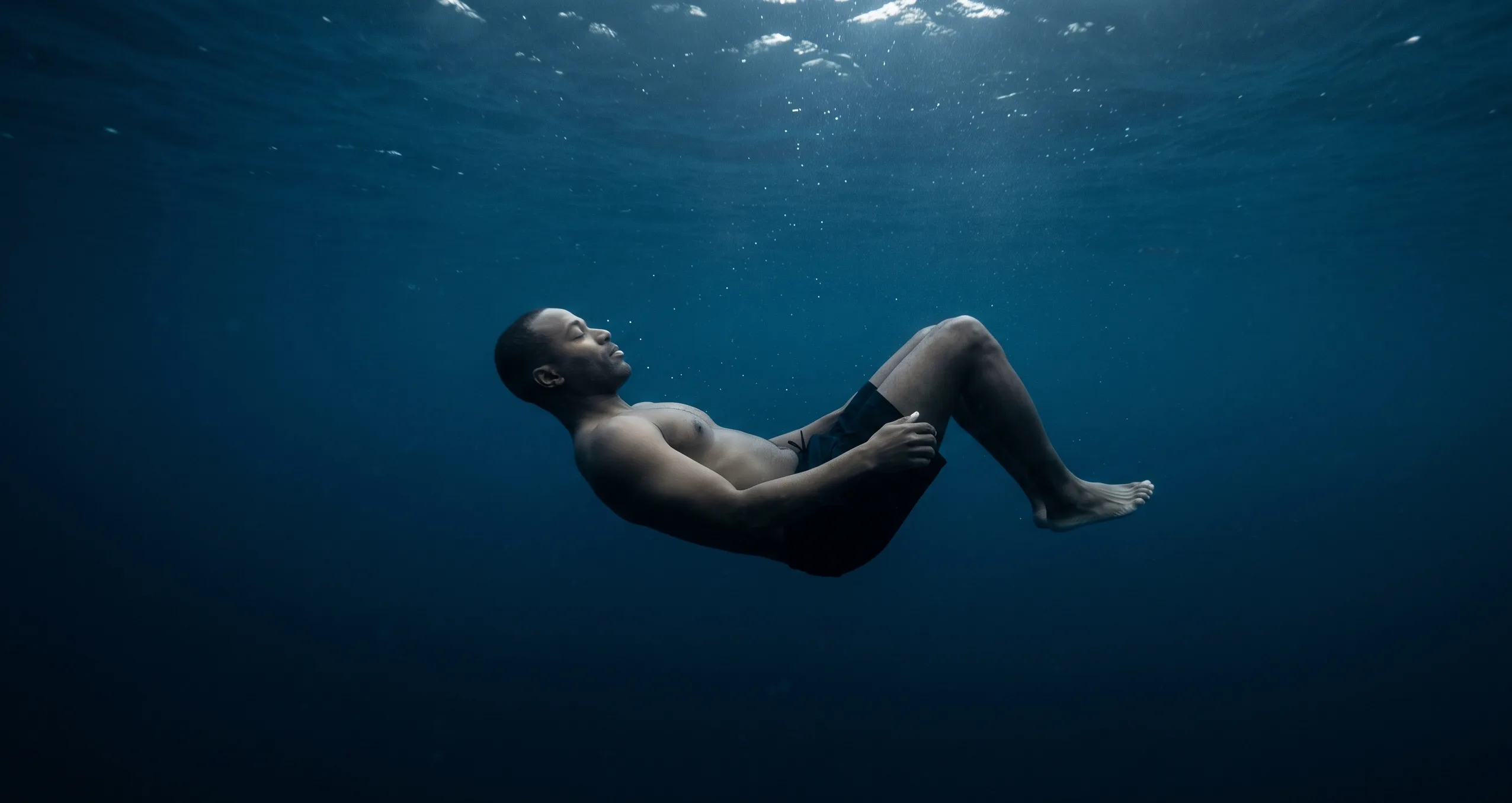L'ivresse des profondeurs — homme suspendu sous l'eau entre surface et abîme